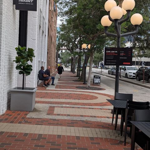 The brick sidewalk outside Bad Mother coffee bar on 1st Avenue South, with the session board further down the street.